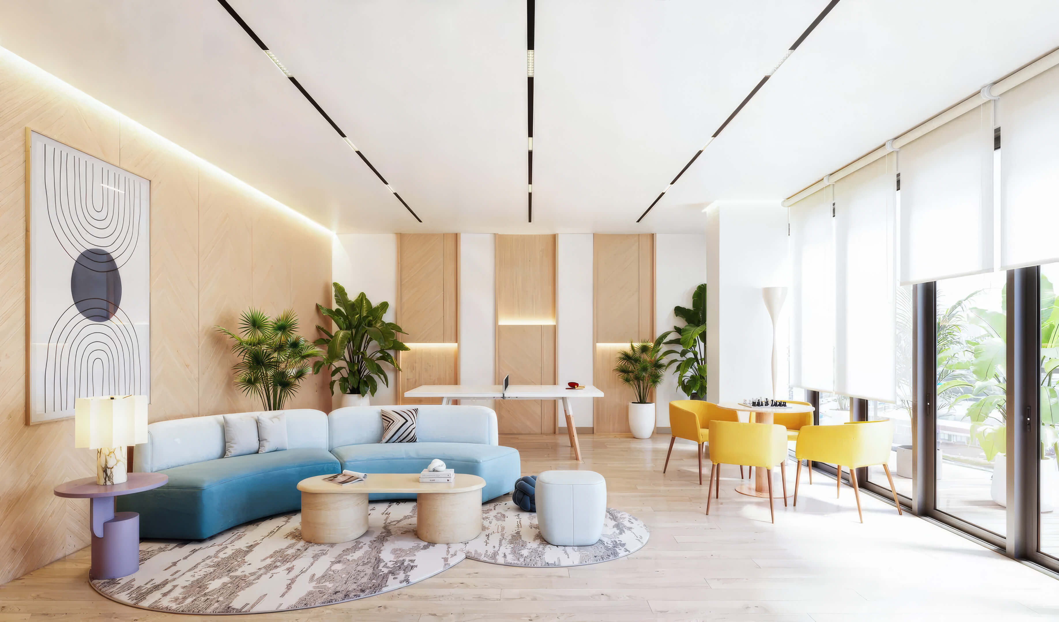 Modern lounge and game area at EDEN Residences with blue sofa, bright windows and contemporary design